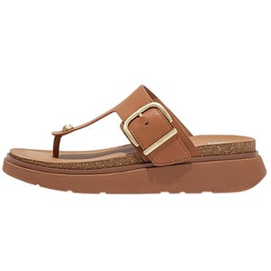 A brown sandal with a thong strap design, elevated sole, and a large gold buckle on the side.