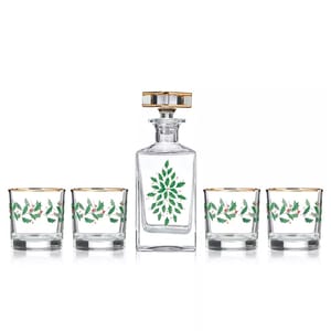 A set includes a whiskey decanter and four glasses, each adorned with green holly and red berry motifs and gold trim.