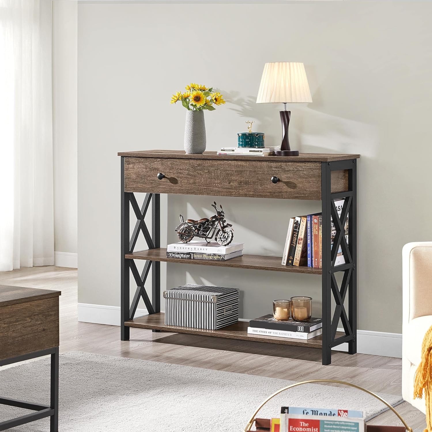 A wooden console table with two shelves, displaying decorative items such as a lamp, books, and a model motorcycle.