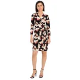 A knee-length, long-sleeve wrap dress with an abstract floral pattern in black, pink, and cream tones, paired with black high-heel sandals.