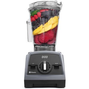 A Vitamix blender filled with various fruits, including raspberries, blackberries, mango slices, and beet slices, ready for blending.