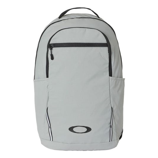 A light gray backpack with a front zippered pocket, side pockets, and a handle on top, featuring a black logo on the lower front.