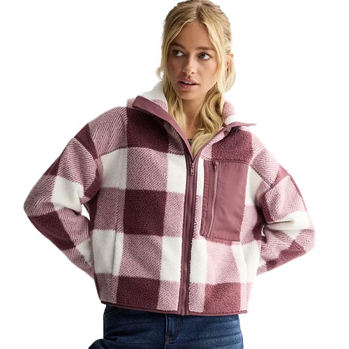 A woman is wearing a zip-up fleece jacket with a pink and white checkered pattern, featuring a front pocket and a high collar.