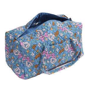 A blue floral quilted fabric duffel bag with a zipper on top, designed for travel or gym use.