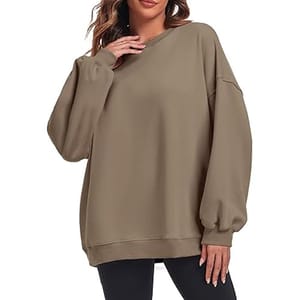 A woman is wearing an oversized brown sweatshirt with long sleeves and relaxed fit, paired with black leggings.