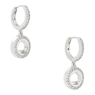 These are silver hoop earrings with a circle and spade-shaped design, embellished with small, sparkling stones. They are called \“Spot The Spade Pave Huggies\“ and have a modern, elegant appearance.