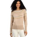 A woman is wearing a beige sweater with a Fair Isle pattern across the chest and shoulders, paired with off-white pants. The sweater features a ribbed neckline, cuffs, and hem.