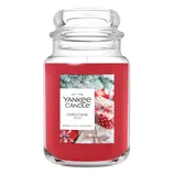 Yankee Candle \“Christmas Eve\“ features a red jar with a festive design of gifts and pine branches, offering a room-filling fragrance.