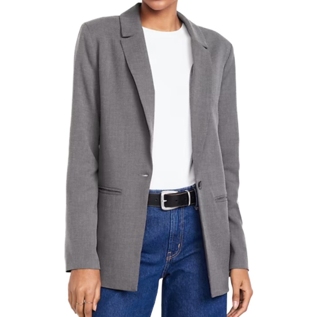 A person is wearing a gray blazer over a white top, paired with blue jeans and a black belt.