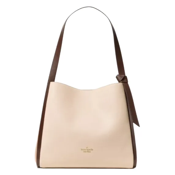 A beige tote bag with a structured design, featuring a brown strap and a minimalist knot detail. The brand logo is subtly displayed at the front.