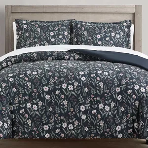 Floral-patterned bedding set with a navy blue background, featuring white and pink flowers, displayed on a wooden headboard bed.