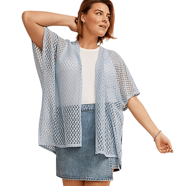 A woman is wearing a light blue, short-sleeved, semi-sheer kimono over a white top and denim skirt.