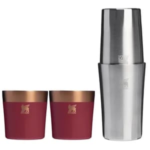 A cocktail shaker set with a stainless steel shaker and two maroon cups featuring a bronze-colored rim.
