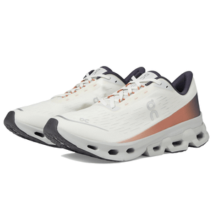 On Women's Cloudspark Running Shoes feature a sleek design with a white body, orange accents, and a distinctive wavy sole. They combine comfort with style, ideal for running and everyday wear.