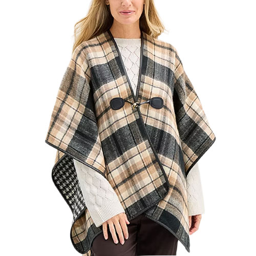 A person is wearing a plaid cape with a black and tan pattern, fastened with a toggle closure over a white sweater.