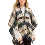 A person is wearing a plaid cape with a black and tan pattern, fastened with a toggle closure over a white sweater.