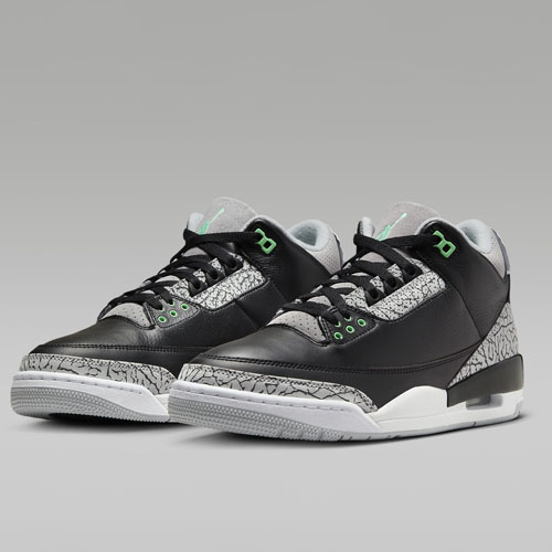 A pair of black and gray sneakers with green accents and a patterned design on the sides and heel.