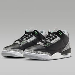 A pair of black and gray sneakers with green accents and a patterned design on the sides and heel.