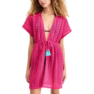 A woman wears a hot pink, open-knit beach cover-up with short sleeves and a drawstring waist featuring blue tassels.
