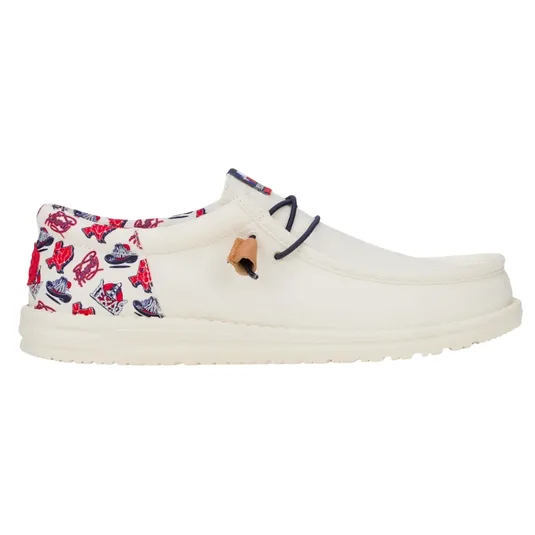 Cream-colored slip-on shoe with a unique red and blue graphic pattern on the heel and collar, featuring dark lace accents and a tan leather detail.