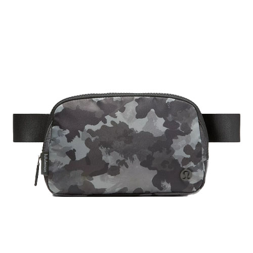 A camouflage-patterned belt bag with a zippered main compartment, featuring a black adjustable strap and subtle branding on the front.