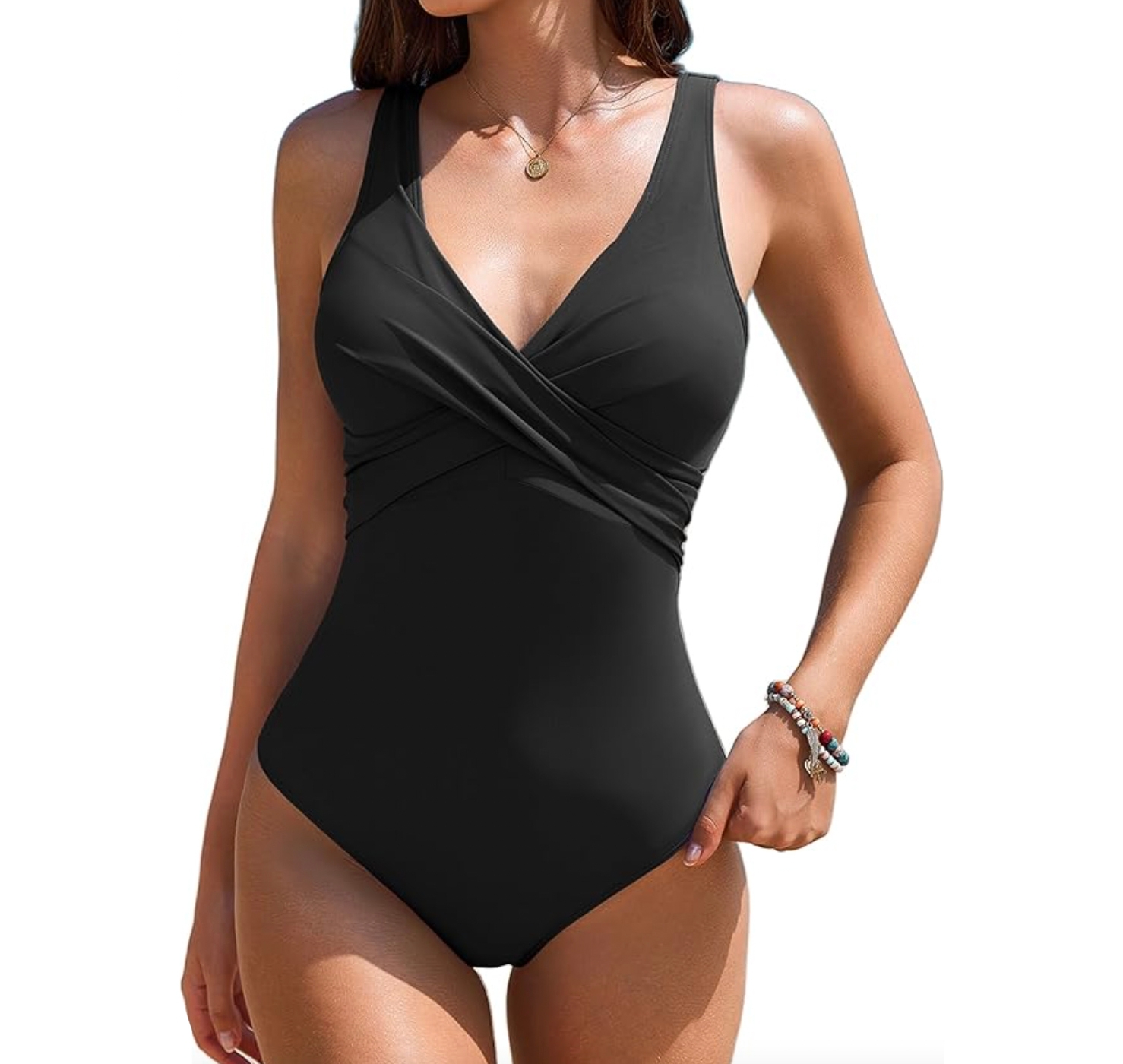 A black one-piece swimsuit with a cross-wrap front design, V-neckline, and thick shoulder straps, accessorized with a small necklace and bracelets.