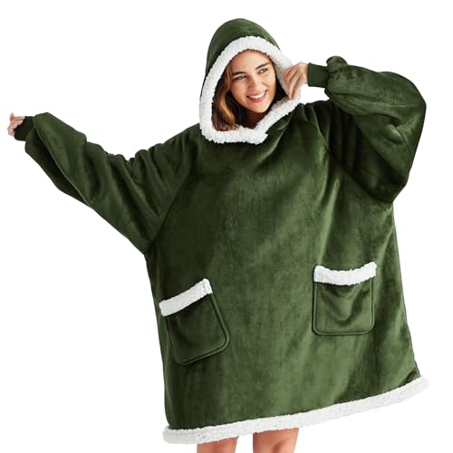 A person is wearing an oversized green hooded wearable blanket with white sherpa lining and two front pockets.
