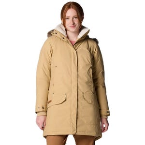 A woman is wearing a beige parka with a fur-lined hood and large front pockets, styled for cold weather.