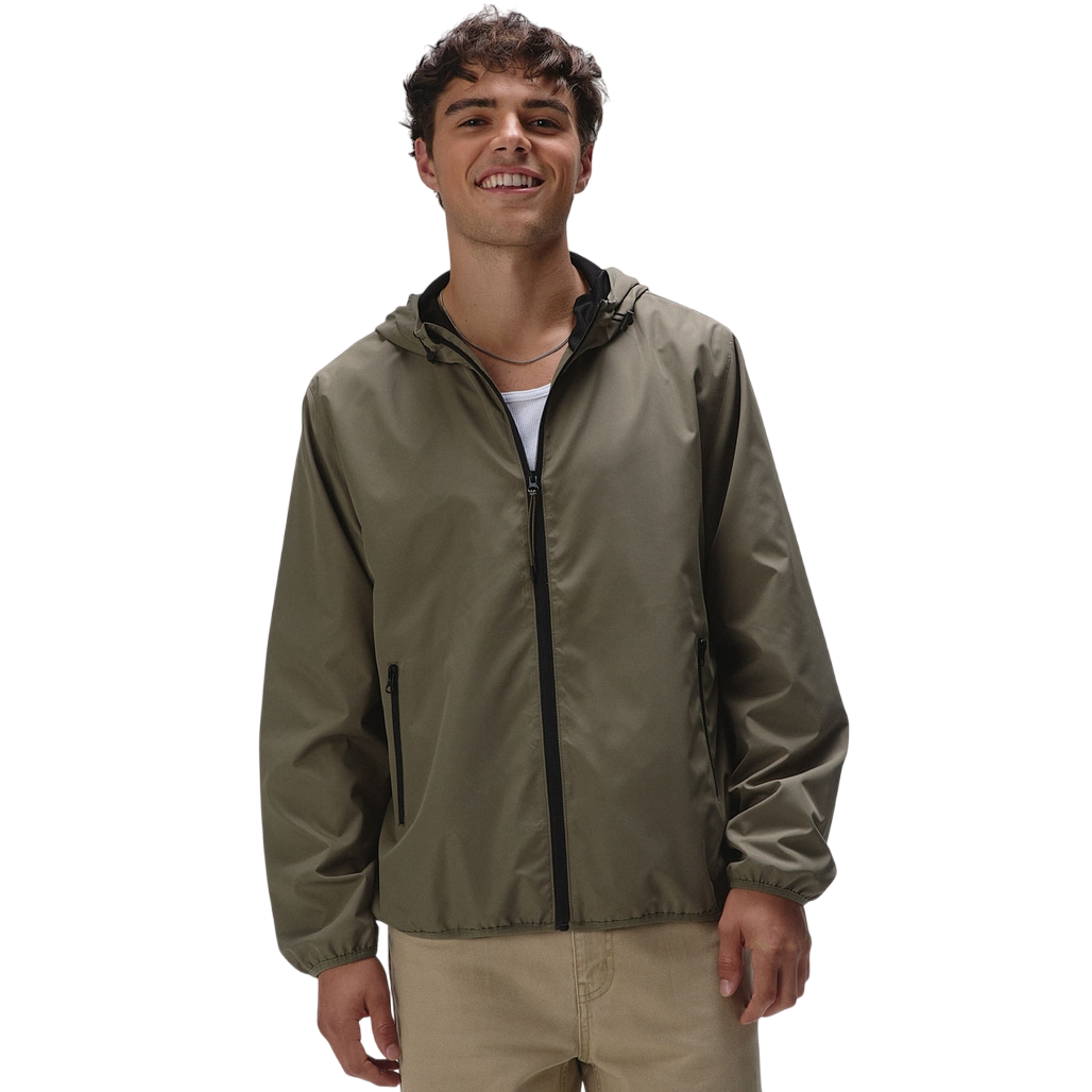 A smiling person is wearing a lightweight, olive green hooded jacket with black zipper details and beige pants.