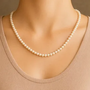 A pearl necklace is shown worn around the neck, displayed over a beige top.