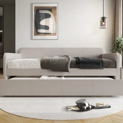 A modern living room featuring a beige sofa, round rug, wall art, a side wall lamp, and a low-profile coffee table with decorative items.