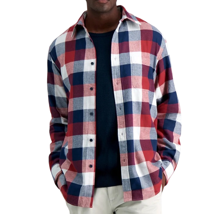 A person is wearing a long-sleeve flannel shirt with a red, white, and blue checkered pattern over a navy sweater, paired with light-colored pants.