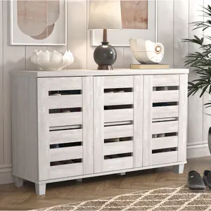 A wooden sideboard with slatted doors, featuring a light finish. It holds decorative items, including a lamp, a shell ornament, and a vase.