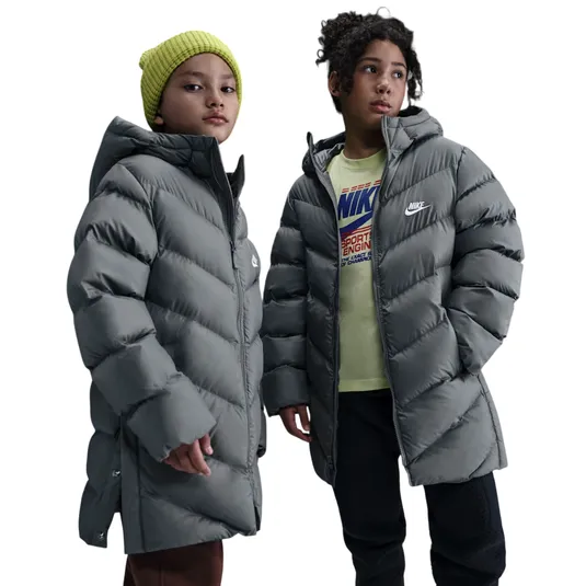 Two children wearing gray Nike puffer jackets. The child on the left has a yellow beanie and the one on the right wears a shirt with a Nike logo.