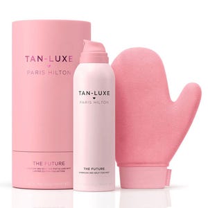 Tan-Luxe Self-Tanning Kit includes a pink bottle of \“The Future\“ airbrush 360 self-tan mist and a matching pink mitt for application. The packaging features collaboration branding with Paris Hilton.