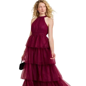 A woman wears a sleeveless, tiered burgundy gown with a halter neckline, complemented by a small black clutch and black heels.