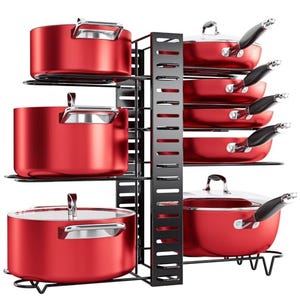 A red cookware set is organized on a tiered, black under-cabinet storage rack with slots for pans and hooks for lids.
