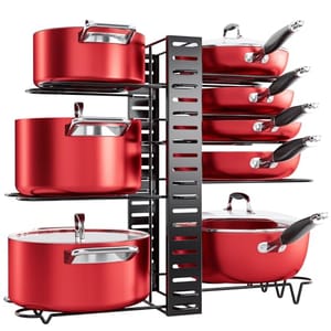 A red cookware set is organized on a tiered, black under-cabinet storage rack with slots for pans and hooks for lids.