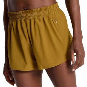 Calia Running Shorts feature a mustard yellow color, elastic waistband, and zip pockets for secure storage.