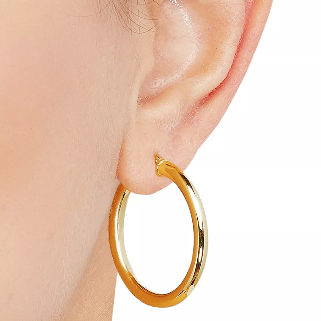 A gold hoop earring worn on an ear, showcasing a smooth, polished finish.