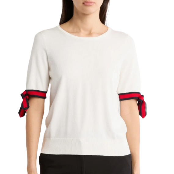 White short-sleeve sweater with black and red striped bow accents on the sleeves, paired with black pants.