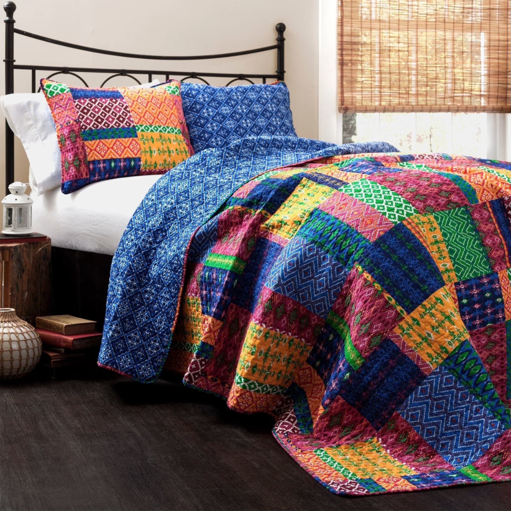 Colorful patchwork quilt and matching pillow on a metal-framed bed, with a wooden floor and bamboo shades in the background.