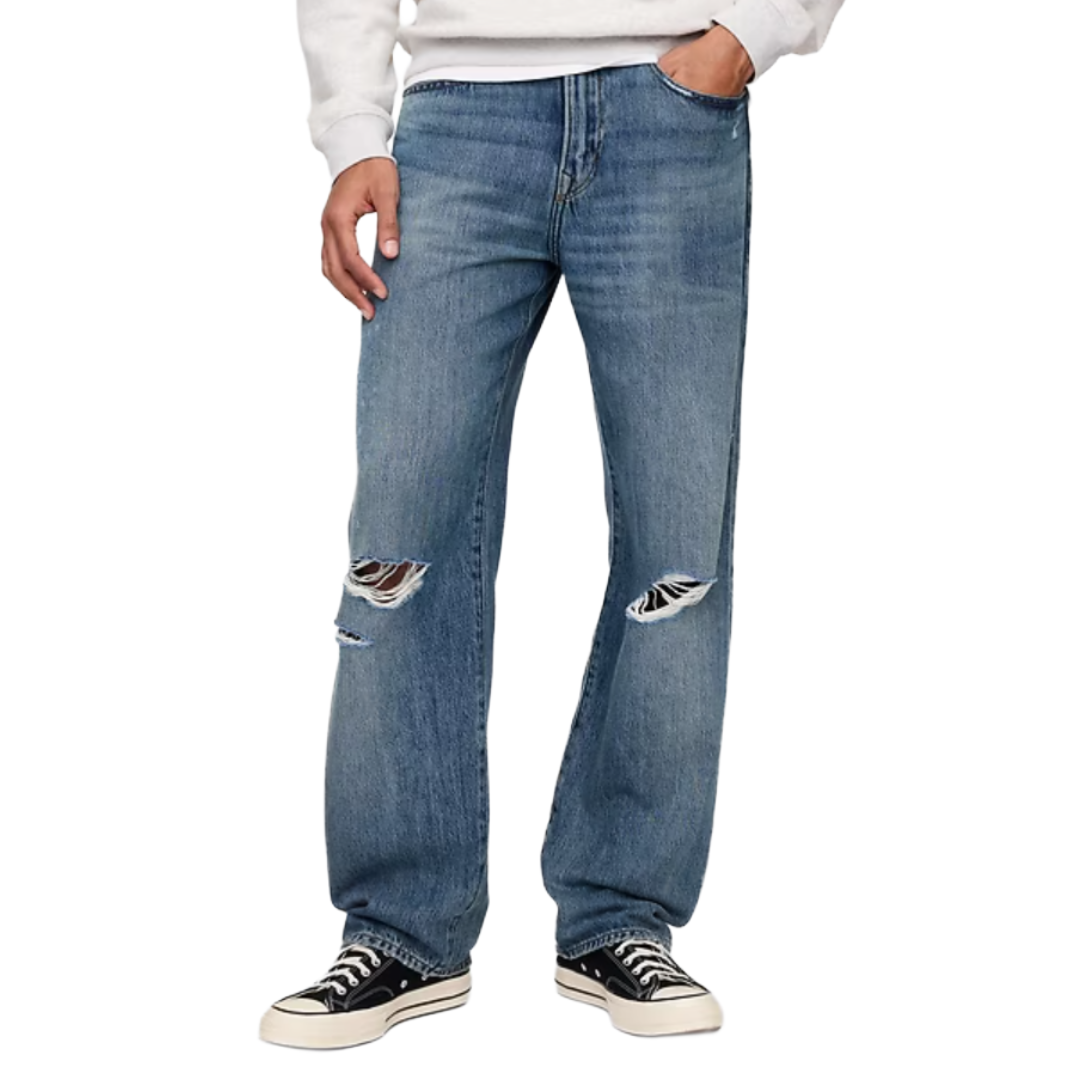 A person is wearing relaxed-fit blue jeans with rips at the knees, paired with a white sweatshirt and black-and-white sneakers.