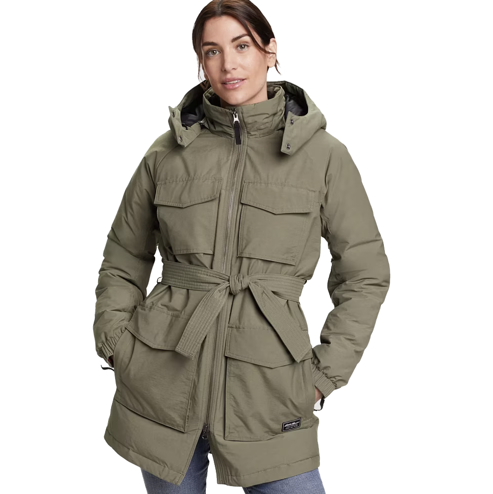 An olive-green parka with a hood, front zipper, large flap pockets, and a belted waist, worn by a model in blue jeans.