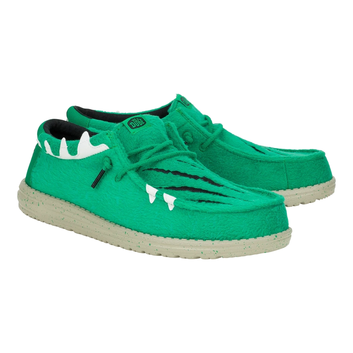 Bright green shoes with a design resembling monster feet, featuring black stripes, white teeth along the side, and the Hey Dude logo on the tongue.