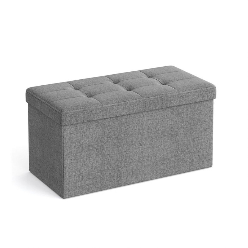 A gray upholstered storage ottoman with tufted cushion top.