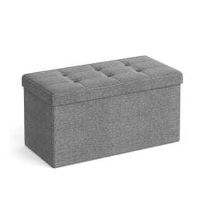 A gray upholstered storage ottoman with tufted cushion top.