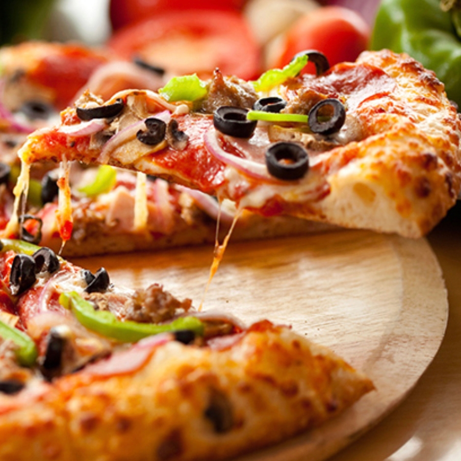 A pizza topped with black olives, green peppers, onions, mushrooms, and pepperoni on a wooden board.