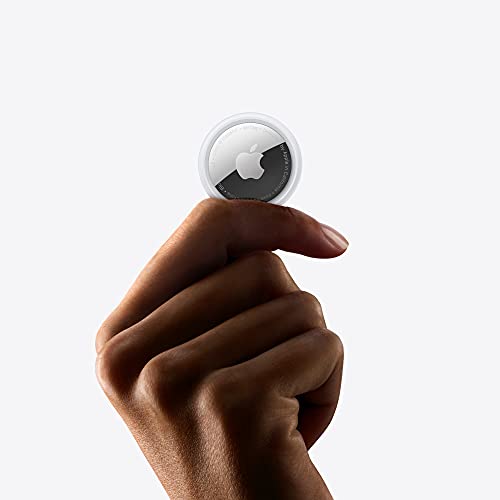 A small, round, silver-and-white device with an Apple logo is being held between fingers.