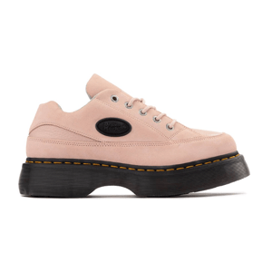 A chunky pink suede platform sneaker with black sole and yellow stitching, featuring a black oval logo patch on the side.